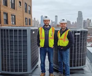 B and Z Heating & Air Conditioning professional HVAC technicians standing with commercial rooftop air conditioning units