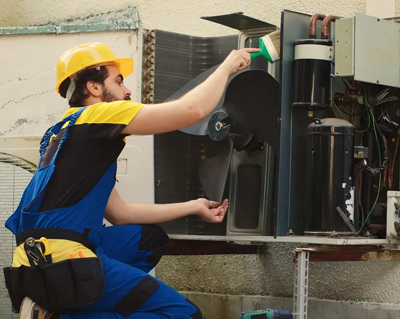 B and Z Heating & Air Conditioning HVAC technician performing professional cleaning and maintenance on outdoor AC unit