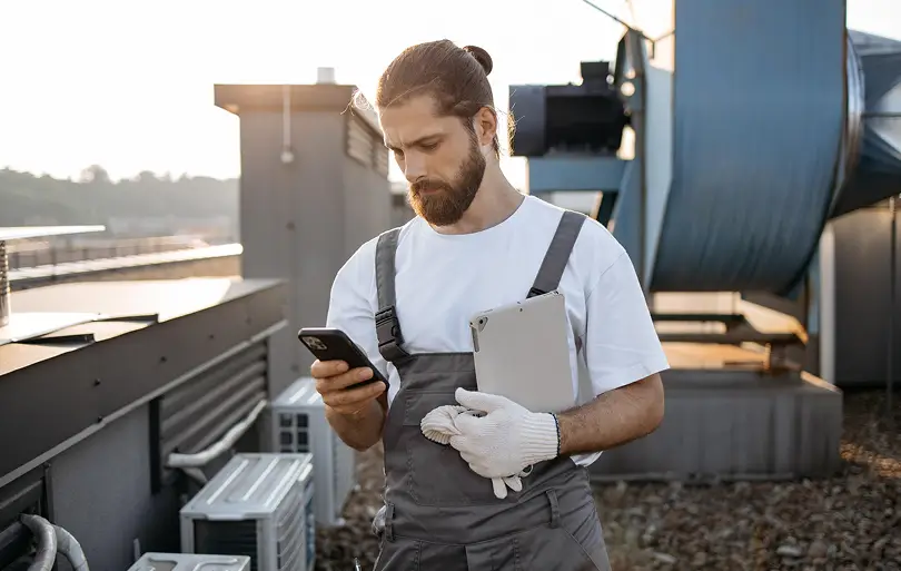 Professional HVAC technician checking system diagnostics on a smartphone