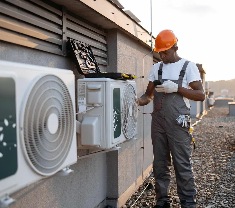 HVAC technician performing electrical diagnostics on outdoor condenser units
